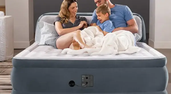 Famille heureuse sur un matelas gonflable, prêt à l'emploi grâce à un aspirateur.