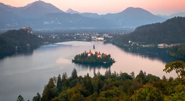 Île avec église et château sur un lac, entouré de montagnes. Un rêve pour visiter la Slovénie.