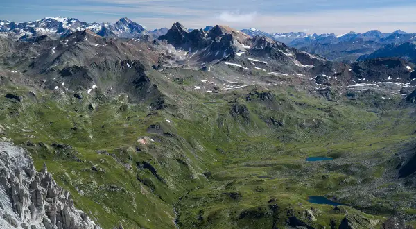 Vue panoramique des Alpes, avec le Mont Thabor en arrière-plan. Des lacs bleus scintillent dans la vallée verdoyante.