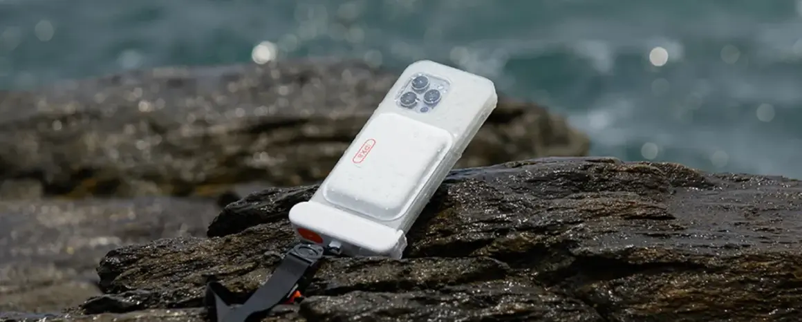 Coque étanche pour téléphone, conforme à la norme IPX8, posée sur des rochers mouillés près de la mer.