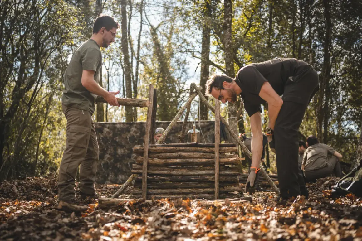 Apprendre comment faire du feu dans la nature : des hommes construisent une structure en bois pour un feu de camp, avec un pot suspendu.