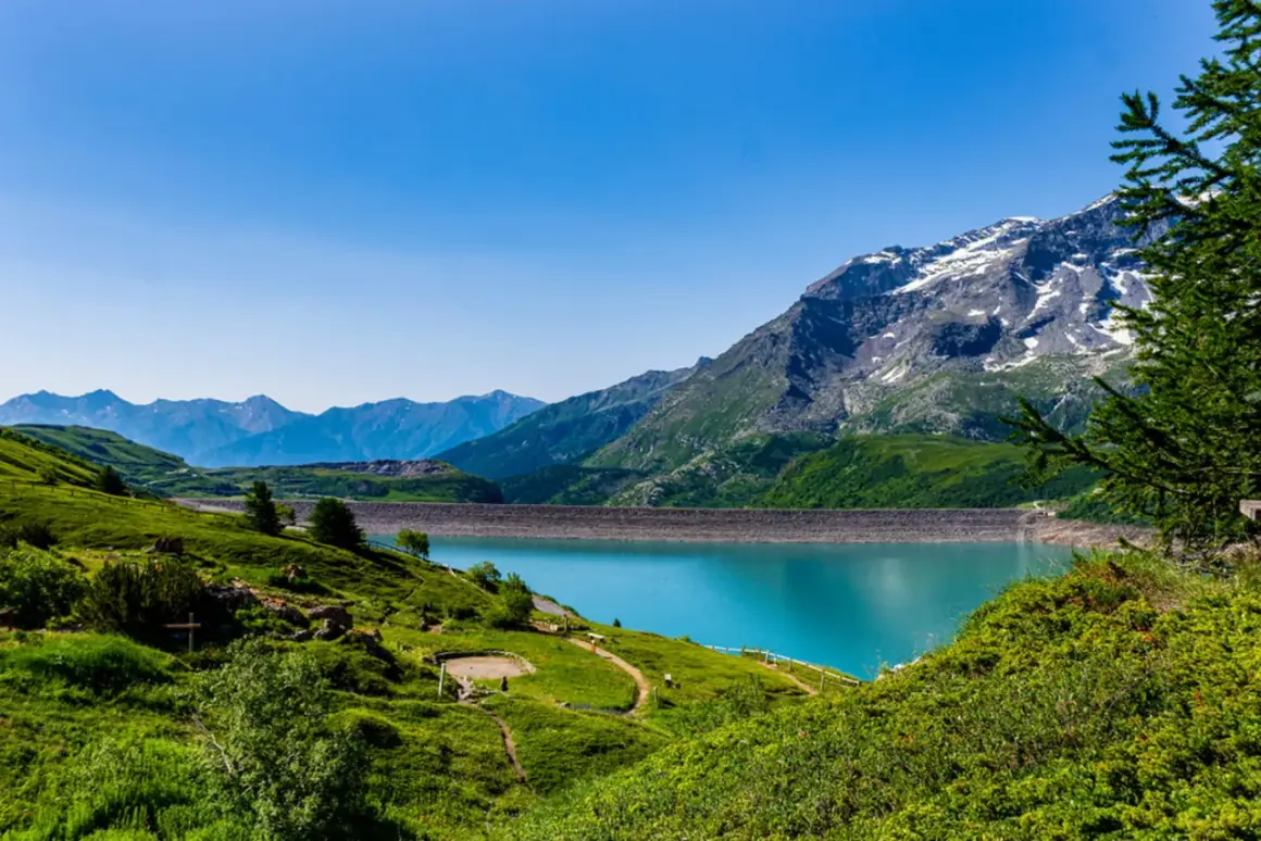 Paysage de montagne spectaculaire avec un lac turquoise et un barrage. Un endroit à voir en Auvergne pour sa beauté naturelle.