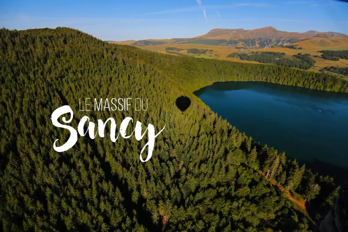 Vue aérienne du lac Estivadoux, niché au cœur du Massif du Sancy, avec une ombre de montgolfière sur la forêt.