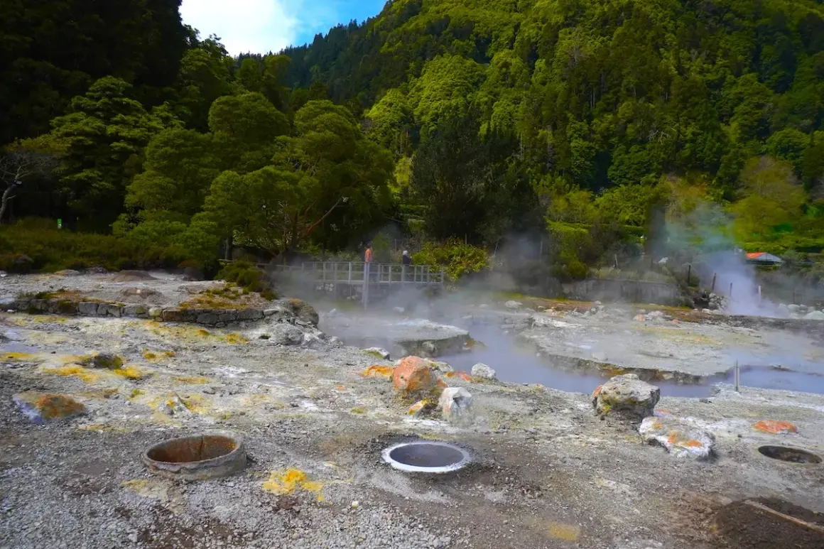 Paysage volcanique des Furnas Açores, avec des fumerolles et des sources chaudes au milieu d'une végétation luxuriante.