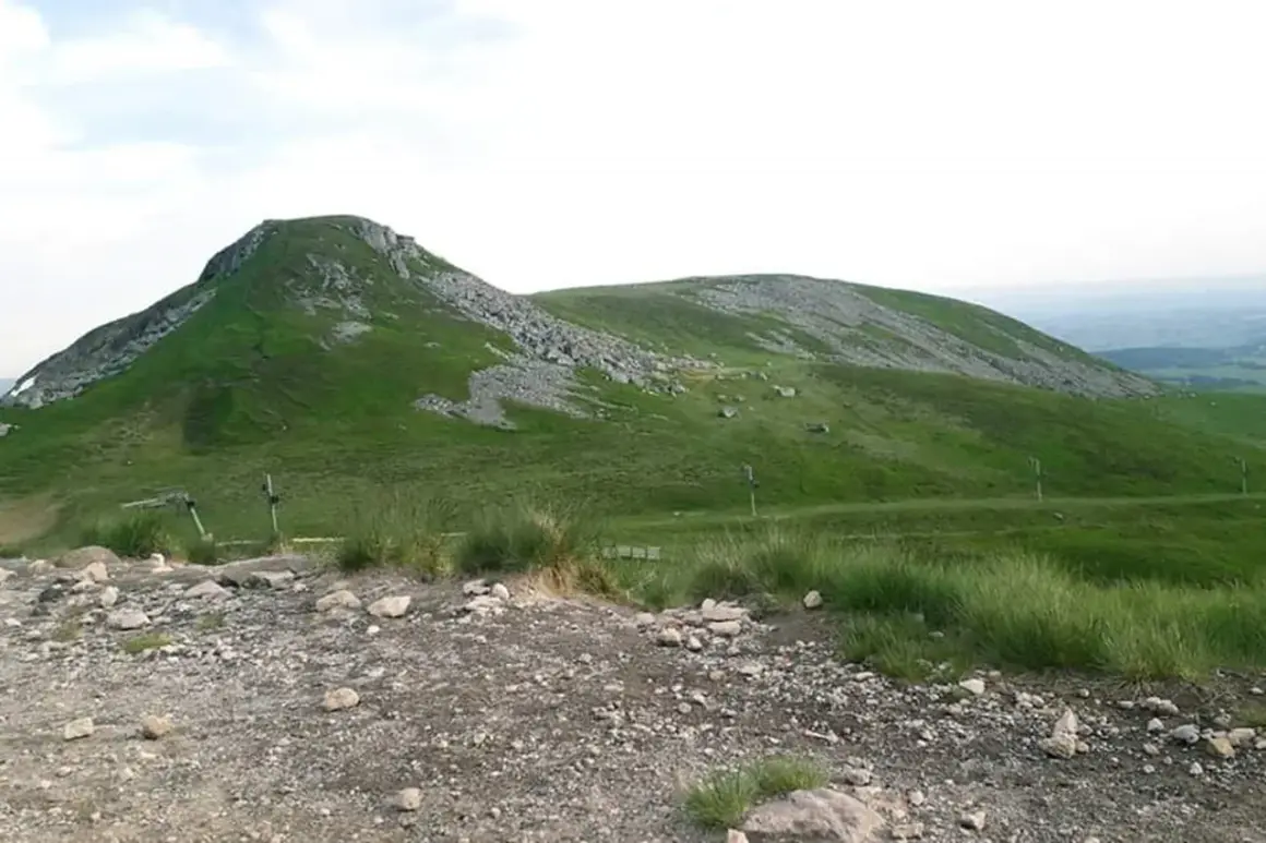 Vue panoramique du Puy de Paillaret, un volcan d'Auvergne aux pentes verdoyantes parsemées de roches.