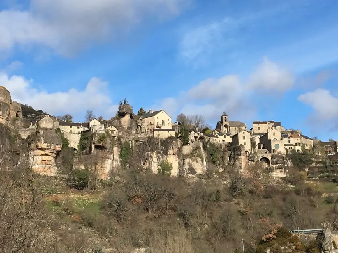 Village perché sur une falaise, un paysage typique du Cantobre Aveyron. Maisons de pierre, église et ciel bleu.
