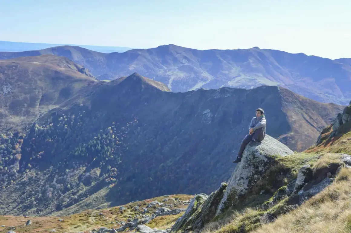 Un homme contemple les paysages grandioses du Cantal, un aperçu de ce que réservent les plus belles randonnées dans le Cantal.