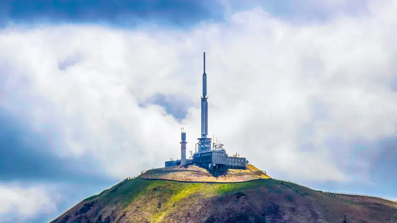 Antenne de télécommunication sur le Puy de Dôme, un sommet emblématique du Massif Central, sous un ciel nuageux.
