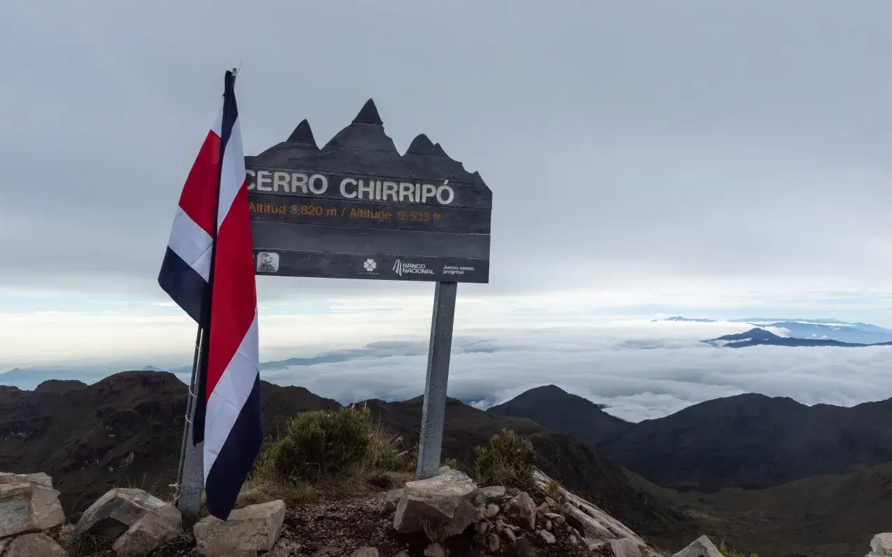 Drapeau du Costa Rica au sommet du Cerro Chirripó, dominant une mer de nuages.