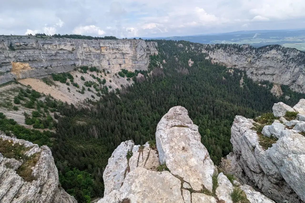 Vue spectaculaire d'une falaise et d'une for&ecirc;t dense, parfaite pour une randonn&eacute;e boucle 5 jours dans le Jura.