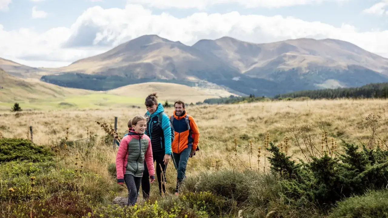 Une famille randonne dans les paysages magnifiques de l'Auvergne en &eacute;t&eacute;. Id&eacute;al pour savoir o&ugrave; aller en Auvergne l'&eacute;t&eacute;.