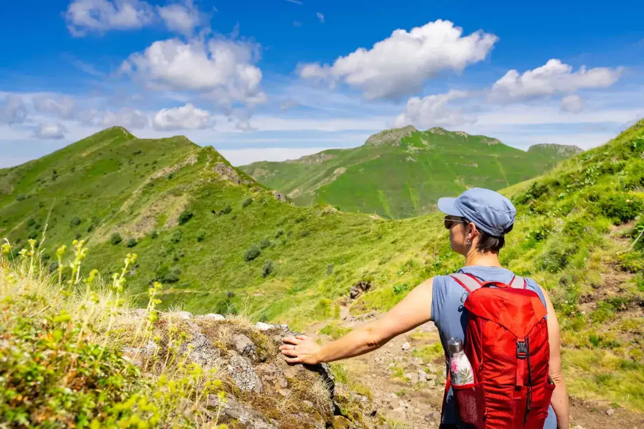 Randonneuse admirant les paysages verdoyants, un aperçu des plus belles randonnées dans le Cantal.