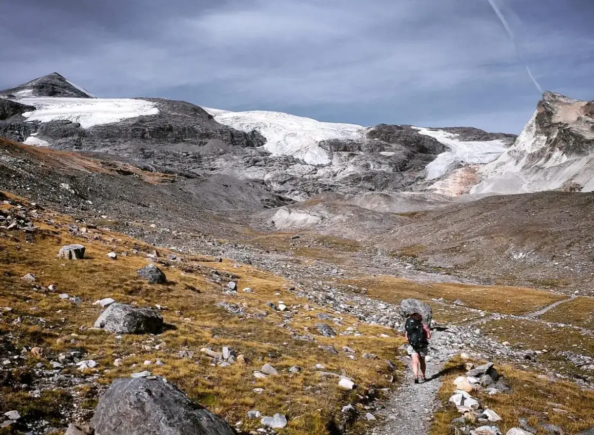 Randonneuse sur un sentier rocailleux, face &agrave; un glacier imposant. Une aventure en boucle randonn&eacute;e 5 jours s'annonce.