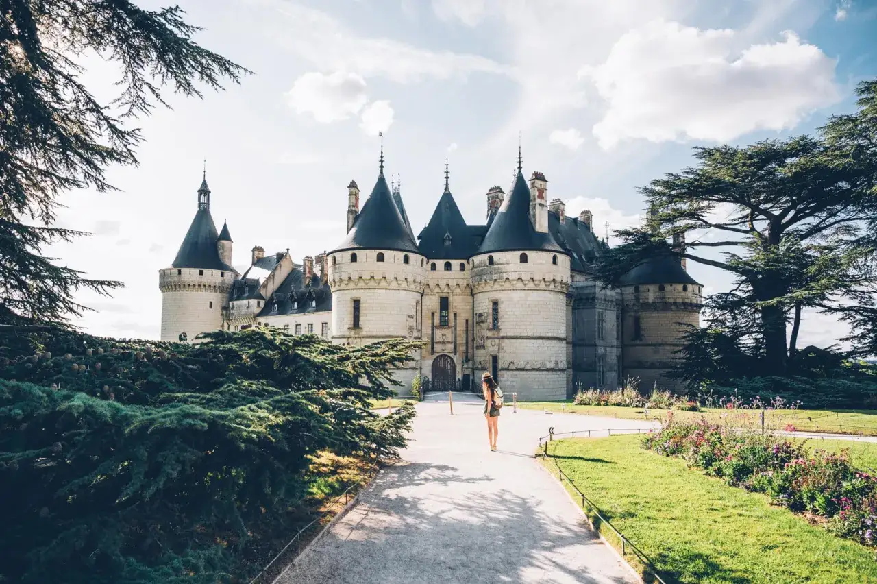 Une femme se promène vers un château majestueux, une belle journée pour visiter le centre de la France.