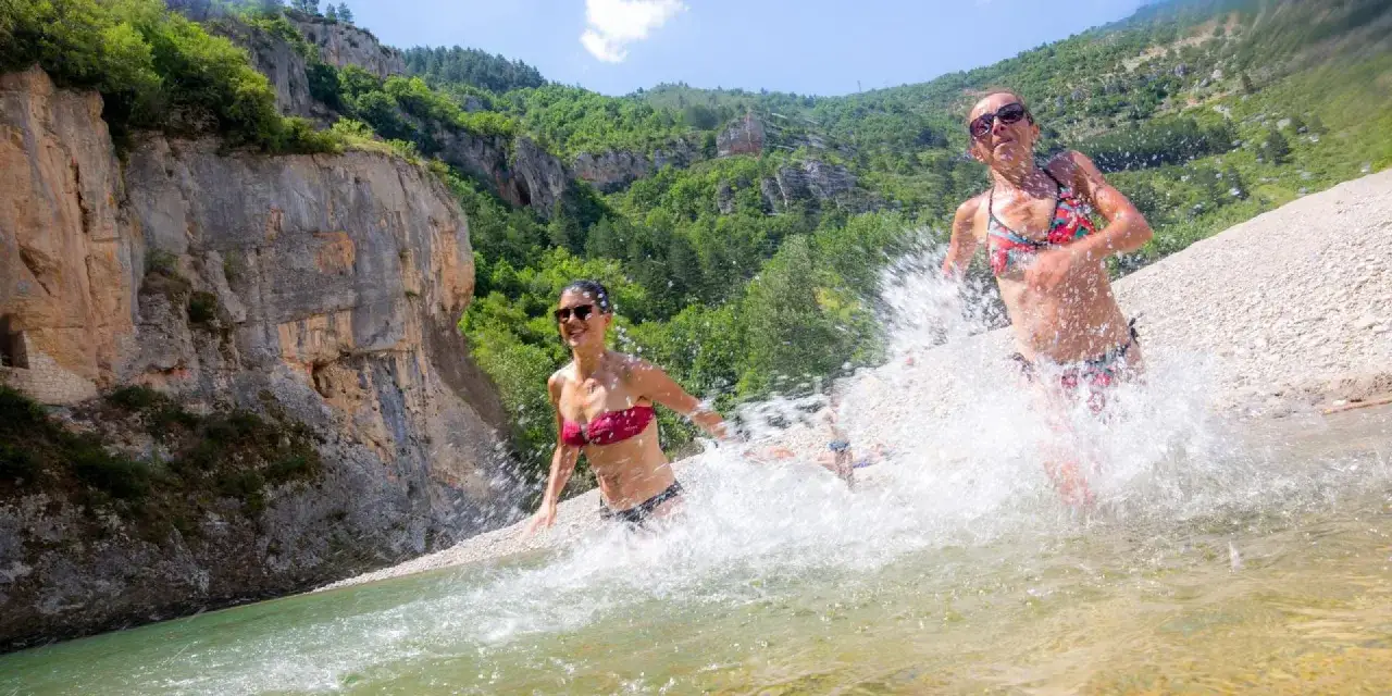 Deux femmes s'amusent dans l'eau vive du lac de Naussac, éclaboussant joyeusement sous le soleil.