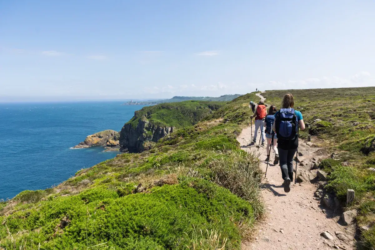 Randonneurs sur un sentier c&ocirc;tier, profitant d'une vue spectaculaire sur la mer lors d'un gr tour de bretagne.