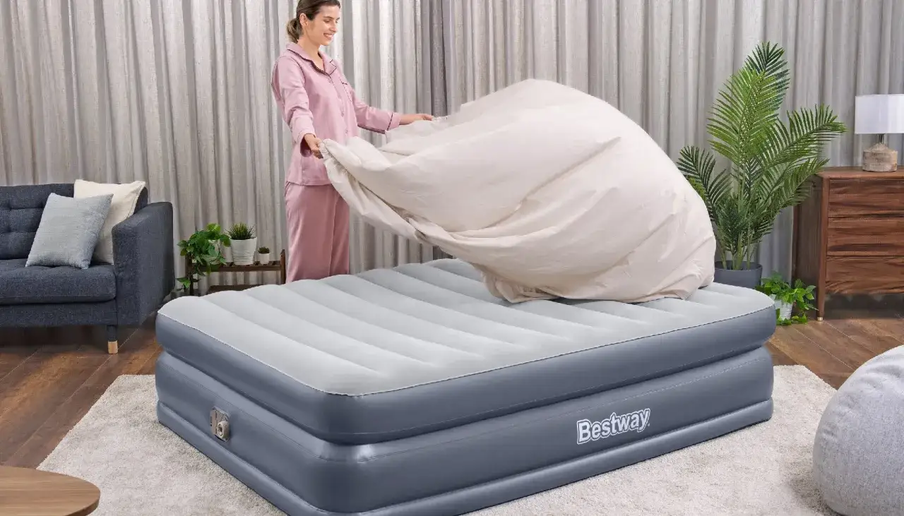 Une femme en pyjama rose met une housse sur un matelas gonflable Bestway. Un guide pour comment nettoyer un matelas gonflable.