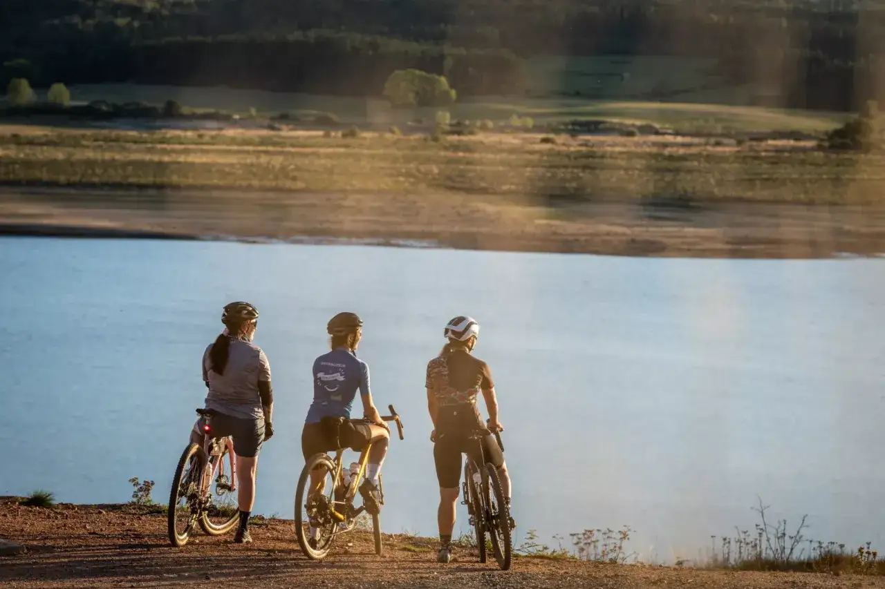 Trois cyclistes contemplent le lac de Naussac, profitant d'une pause lors de leur tour à vélo.