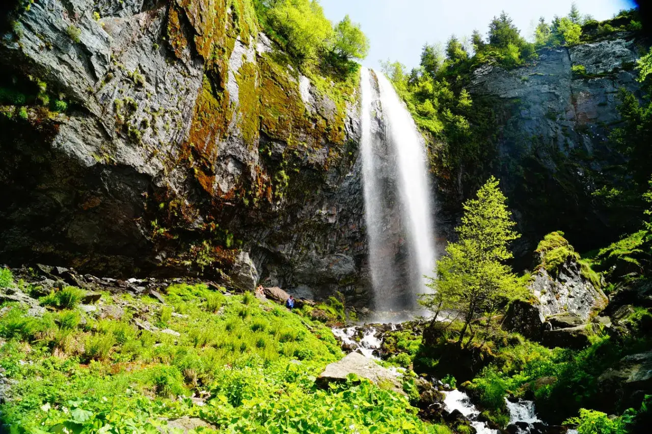 La grande cascade du Mont-Dore d&eacute;vale une falaise rocheuse couverte de mousse. Un sentier verdoyant m&egrave;ne &agrave; son pied.