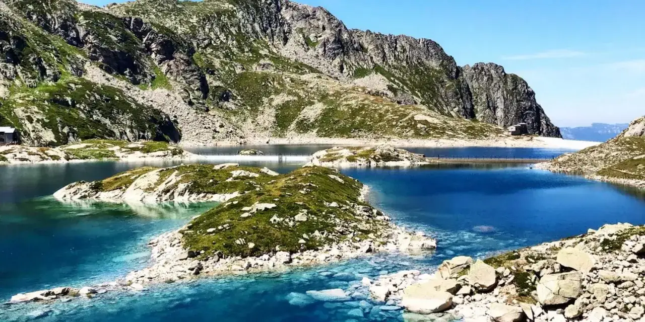 Magnifique paysage du tour des lacs des 7 Laux. Des eaux bleues intenses bordées de rochers et de verdure, avec des montagnes imposantes en arrière-plan.