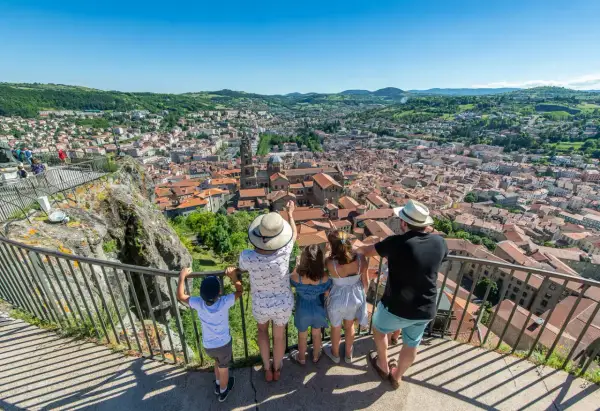 Une famille admire le panorama de la ville. Que voir au Puy en Velay ? La cathédrale et ses toits de tuiles rouges s'étendent à perte de vue.