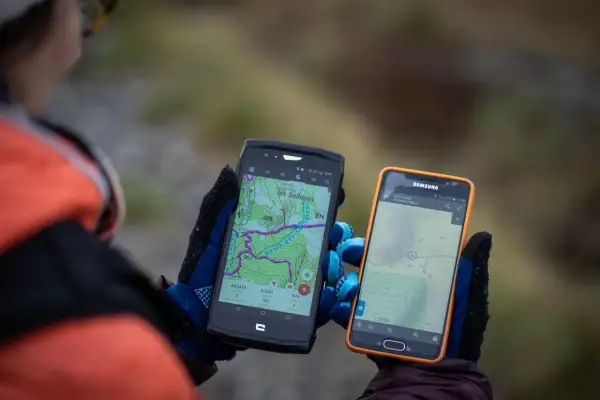 Deux smartphones affichent des cartes topographiques, un **GPS piéton** sur un iPhone et un autre appareil. Idéal pour la randonnée.