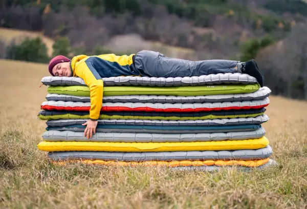 Un homme dort sur une pile de matelas gonflables. Il semble qu'il ait attendu longtemps pour savoir combien de temps laisser gonfler un matelas.