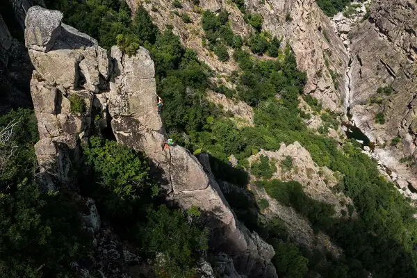 Escalade dans les gorges du Bramont. Deux grimpeurs évoluent sur un piton rocheux, entourés de végétation luxuriante.