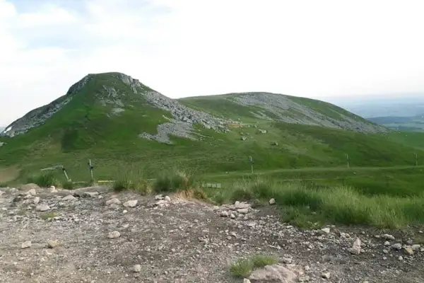 Vue panoramique du Puy de Paillaret, un volcan d'Auvergne aux pentes verdoyantes parsemées de roches.