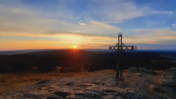 Coucher de soleil sur le moure de la Gardille, avec une croix ornementale veillant sur le paysage.