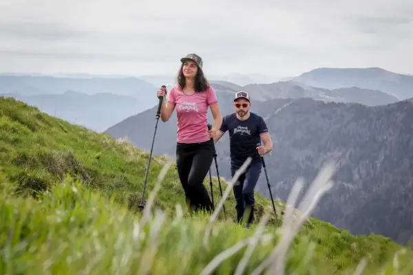 Couple en randonnée en montagne, utilisant des bâtons pour la marche nordique. La différence entre bâton de randonnée et marche nordique est subtile mais importante pour le confort.