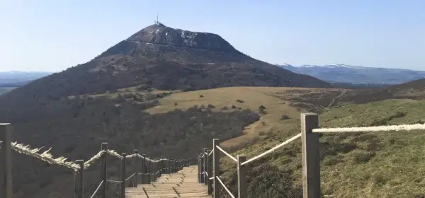Escalier en bois menant au sommet du puy de Dôme, avec une vue panoramique sur les volcans d'Auvergne.