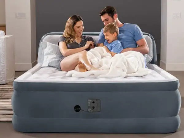Famille heureuse sur un matelas gonflable, prêt à l'emploi grâce à un aspirateur.