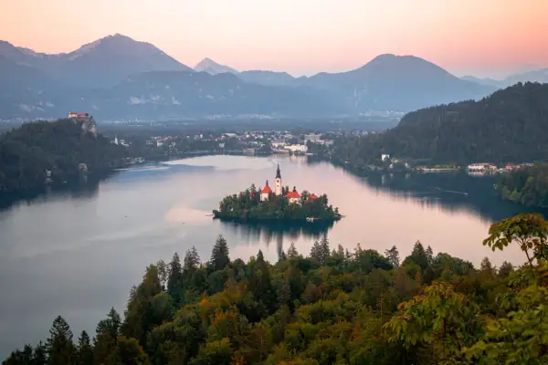 Île avec église et château sur un lac, entouré de montagnes. Un rêve pour visiter la Slovénie.